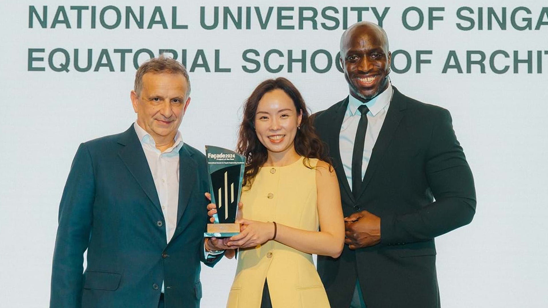 SDE1-SDE3-NetZero-Buildings NUS Architecture Alum Victoria Thong (centre) received the award on behalf of the project team. Pictured with (right) Emmanuel Sonubi, event host, and (left) Steve Bosi, Head of Facade Engineering from WSP. (Photo courtesy of SFE)