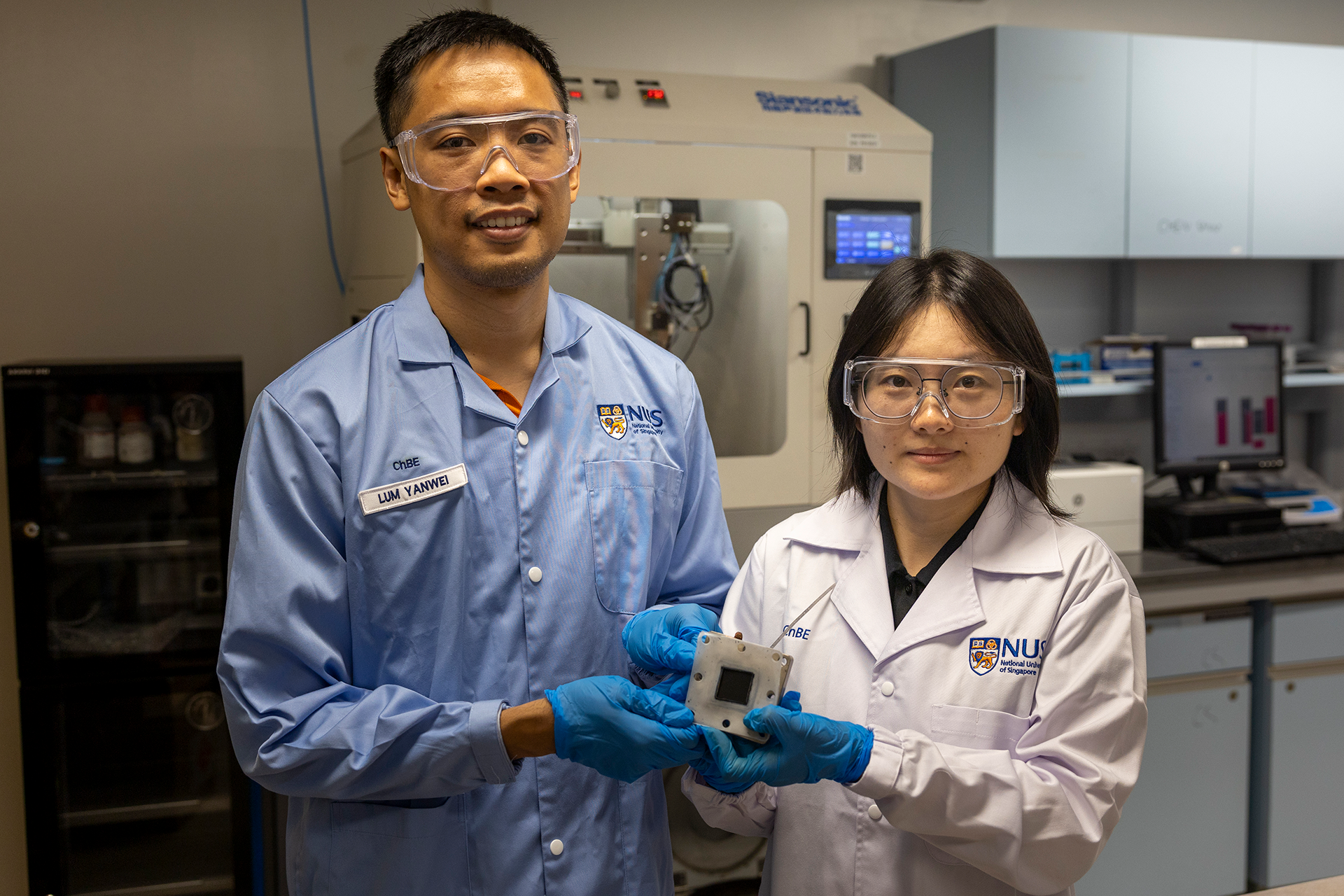 Assistant Professor Lum Yanwei (left) with Yang Qin (right), first author of the research, holding a sample of the catalyst they developed.