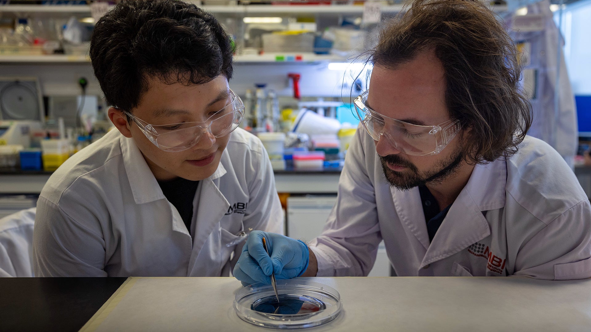 JPEG image-4985-9C66-CD-0 Asst Prof Andrew Holle (right) and PhD student Gao Xu (left), first author of the research paper, discuss features on the silicon wafer containing the mould of their microchannel device.