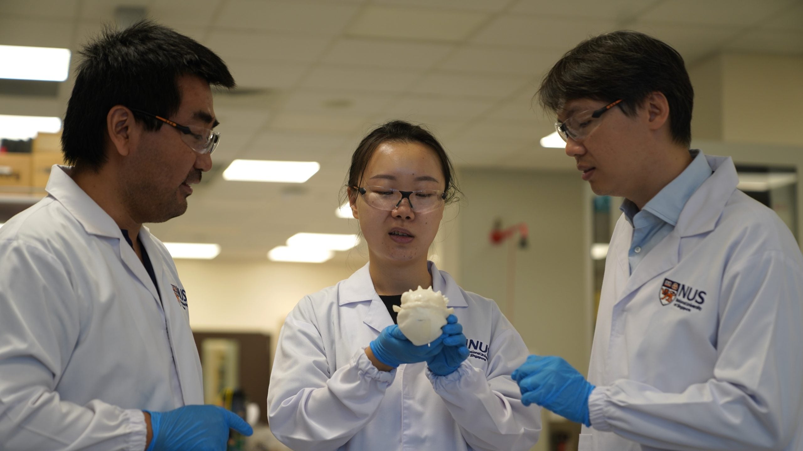 Assoc Prof Benjamin Tee (right), Mr Liu Mengmeng (left), Ms Yu Kelu (centre) and their team have developed the ReSURF sensor – an ultrafast, stretchable, self-healing and recyclable sensor for real-time water quality monitoring – and tested it on a pufferfish-like soft robot.
