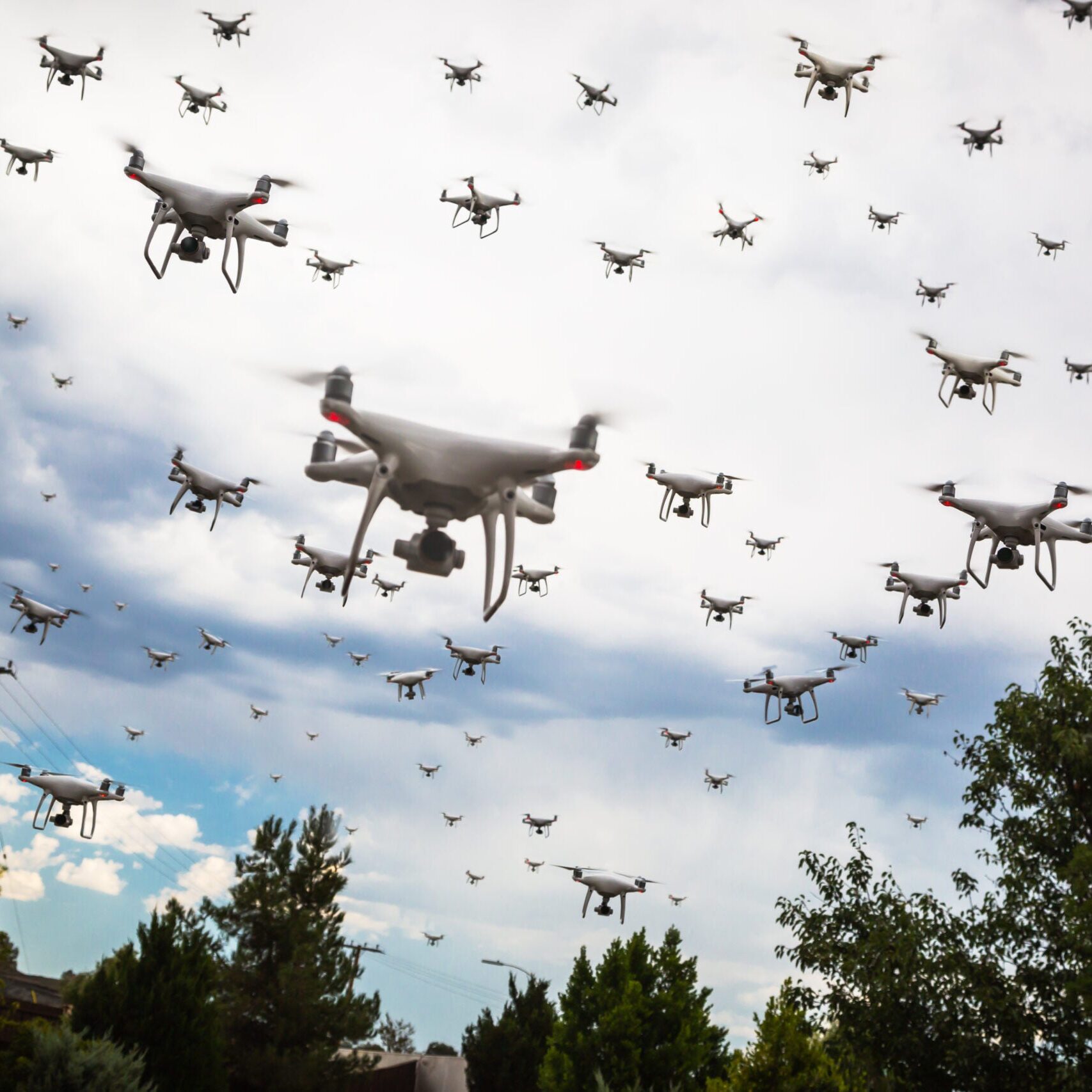 Dozens of Drones Swarm in the Cloudy Sky.