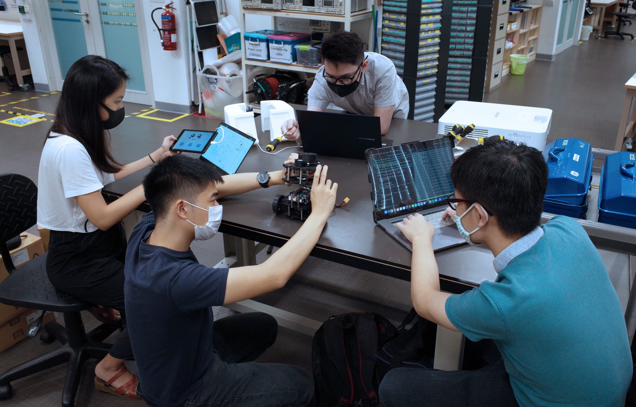<div>iDP students (clockwise from left) Shirley Wang, Michael Sutanto, Steven Wijaya and Andrew Wijaya putting together the hardware and software components of Ah Bot, a moving robot that keeps elderly</div><div>people company and helps look out for their safety when there is no one around.</div>
